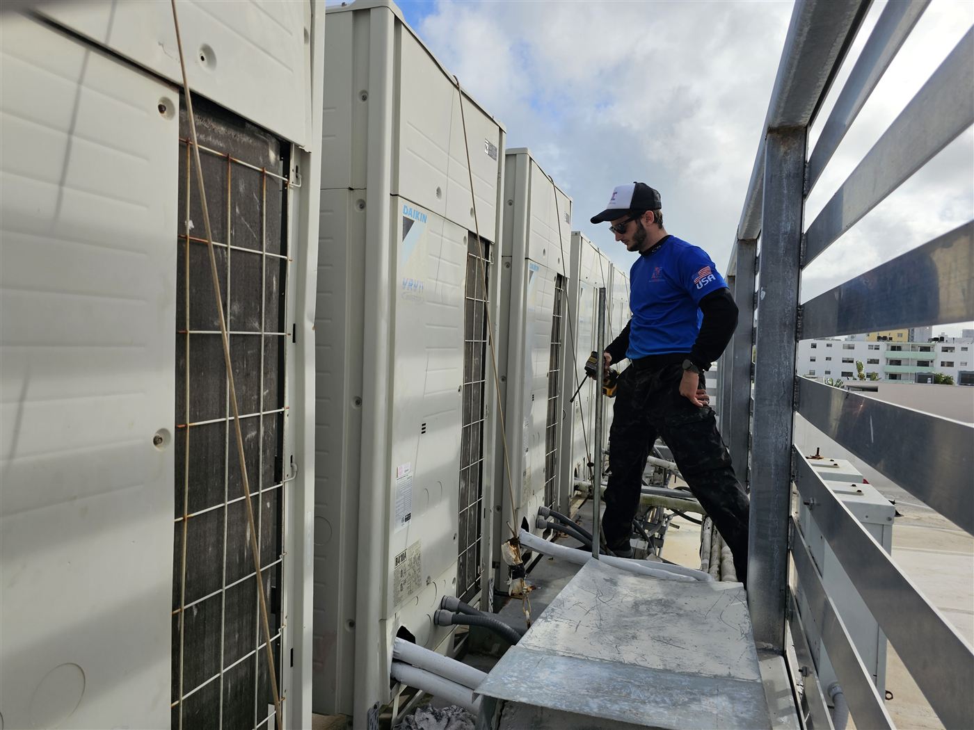 Technician servicing a row of Daikin VRV systems on a rooftop